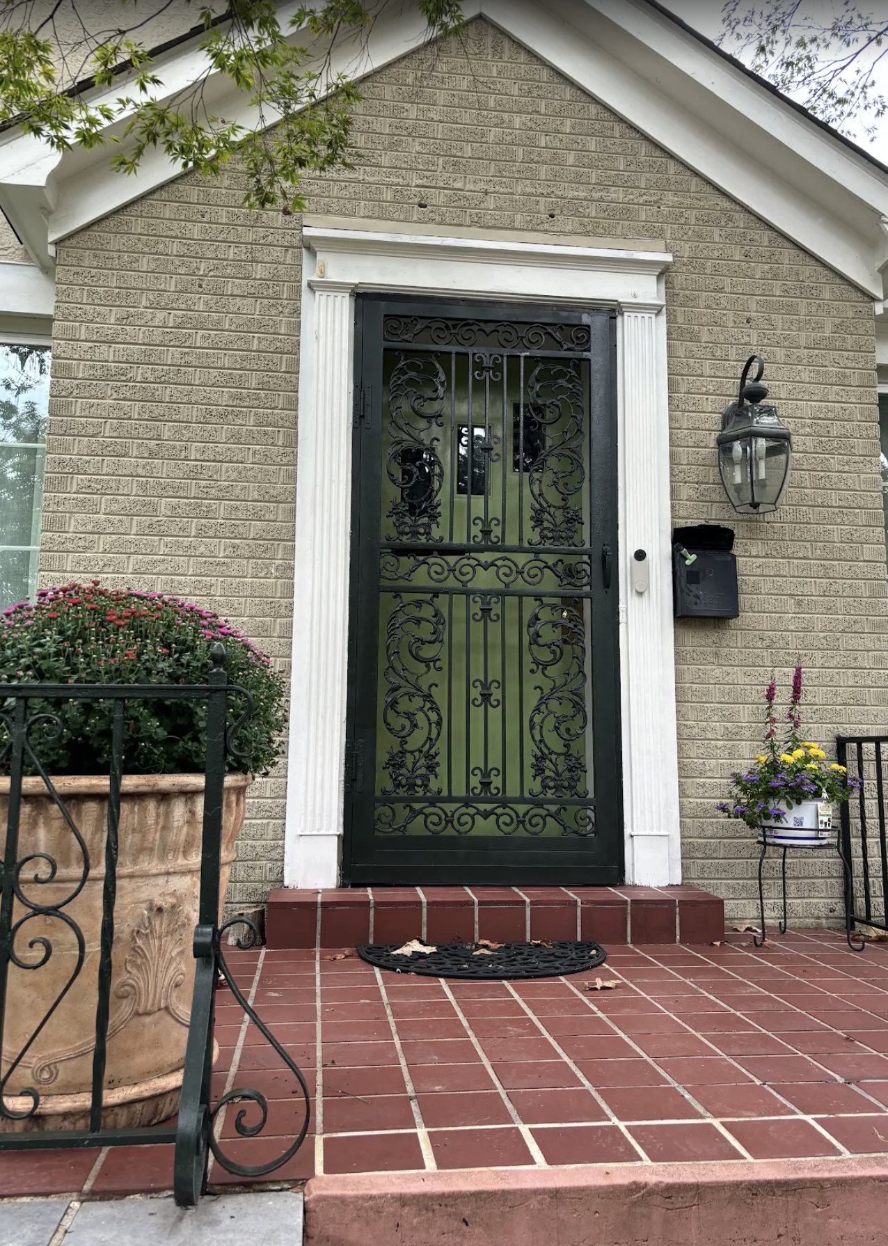 Brick cottage front entry with white painted trim and a black iron door